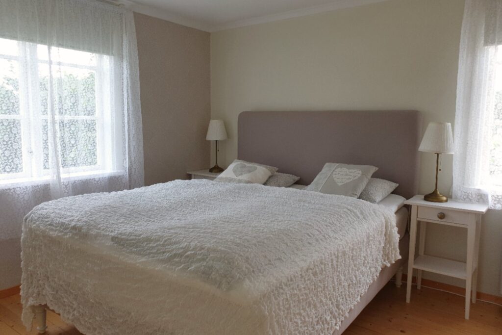 Sovrum i Farm med dubbelsäng, ljusa textilier och fönster mot omgivningen