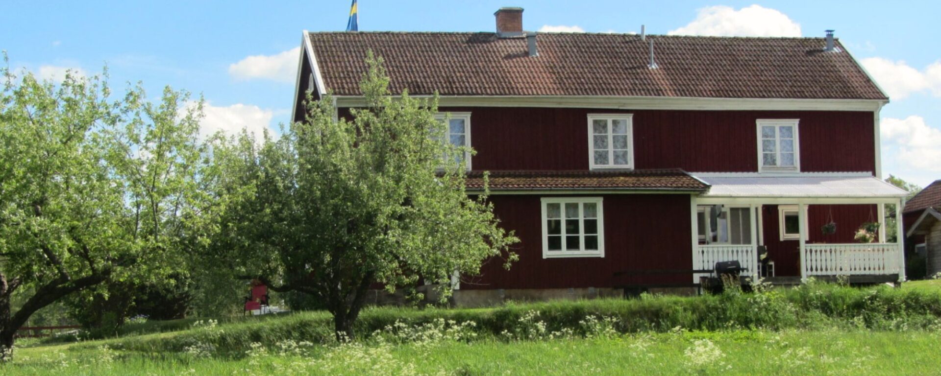 Det röda huset Farm på Snokebo Gård, omgivet av grönska och ängar nära sjön i Småland