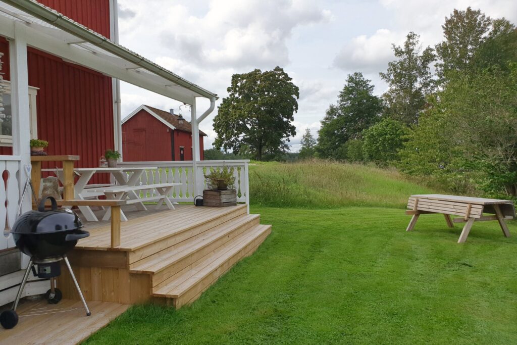 Altan vid Farm med sittplats, grill och utsikt över trädgården