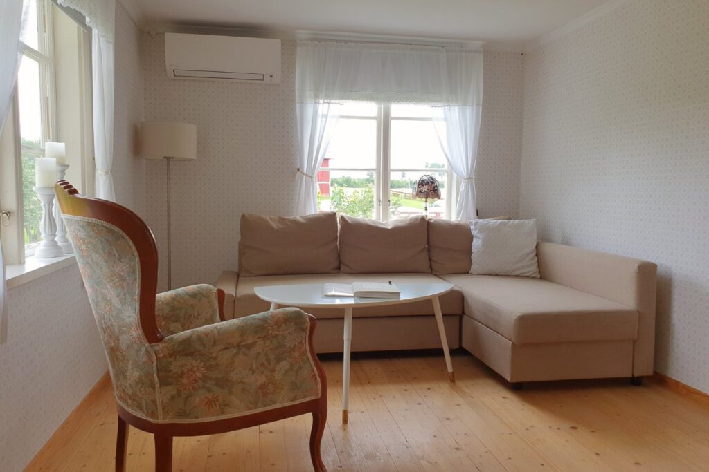 Vardagsrum i Farm med soffa, fåtölj och ljus från stora fönster