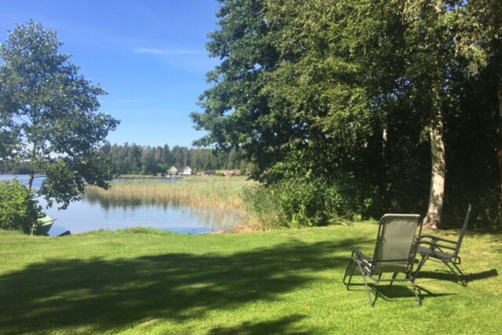 Trädgård vid sjön med sittplatser i gräset