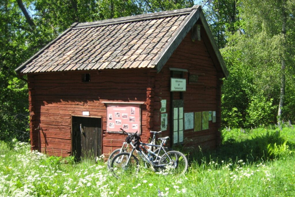 Litet rött hus och cyklar längs en skogsväg i Småland nära Snokebo
