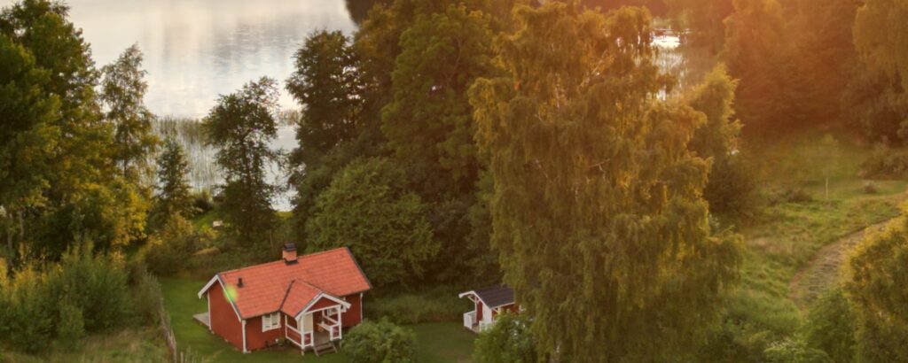 Torpet på Snokebo Gård – litet rött hus nära sjön i kvällsljus