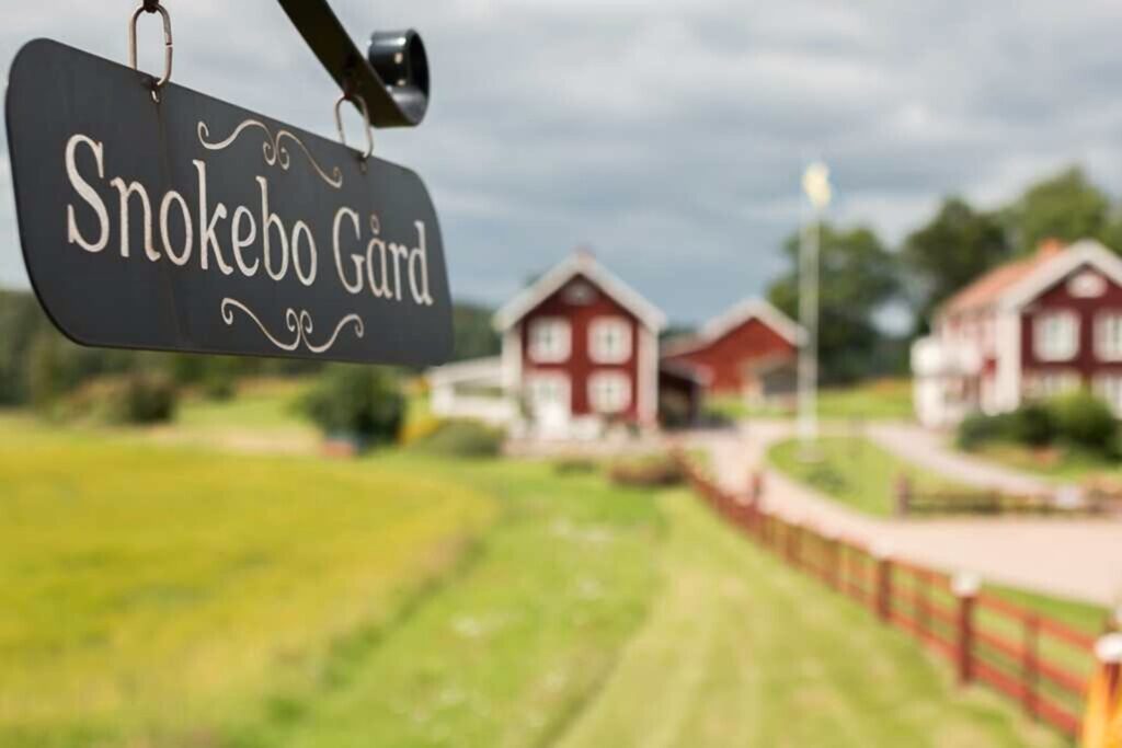 Schild von Snokebo Gård mit Blick auf den Hof und die roten Häuser in Småland