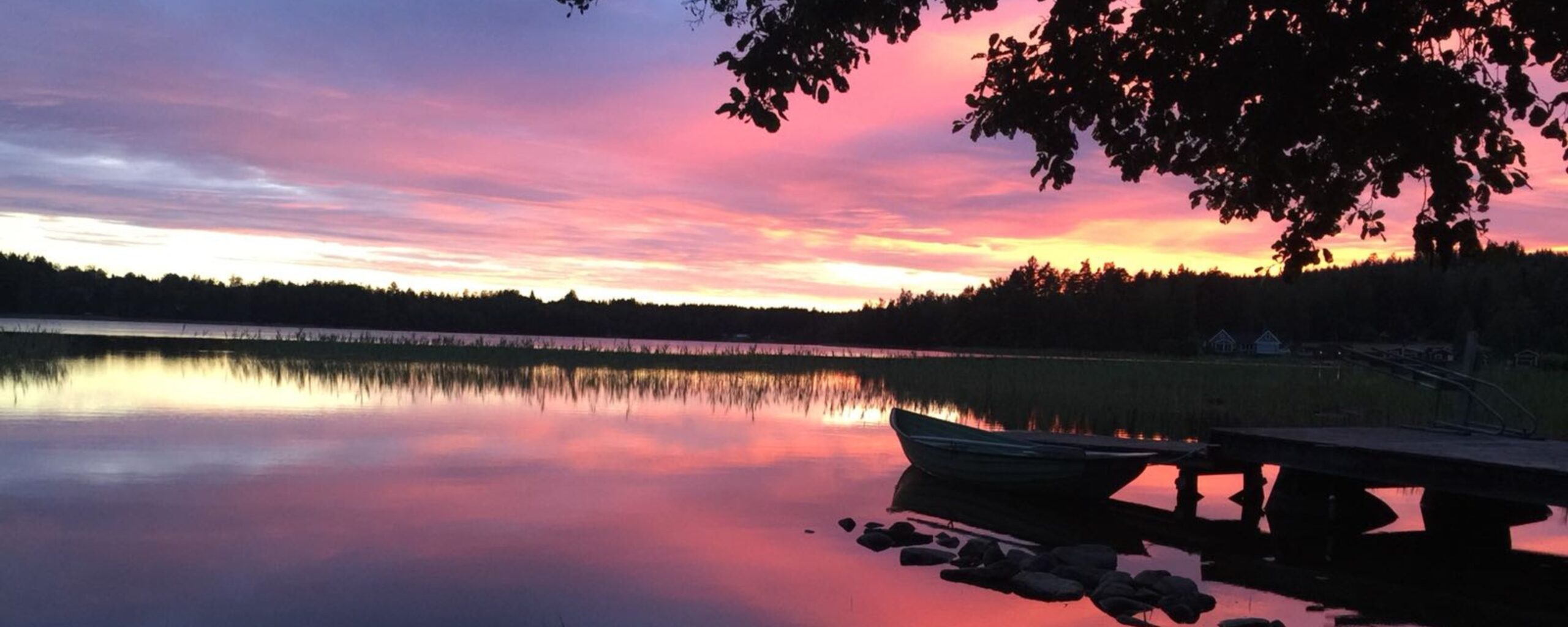 Sonnenuntergang am See Snesaren bei Snokebo Gård in Småland mit Ruderboot am Steg