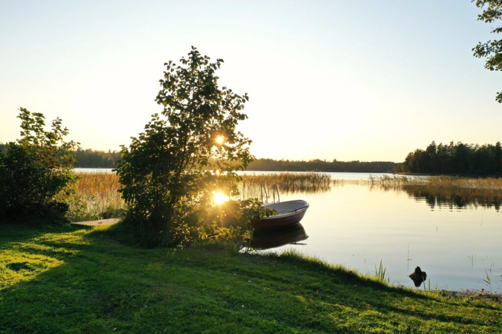 Kvällsljus vid sjön med roddbåt och grönska nära Snokebo Gård