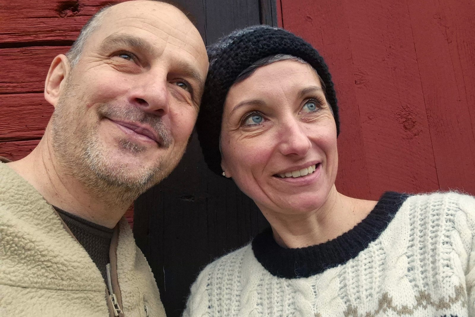 Värdparet på Snokebo Gård framför en röd trävägg