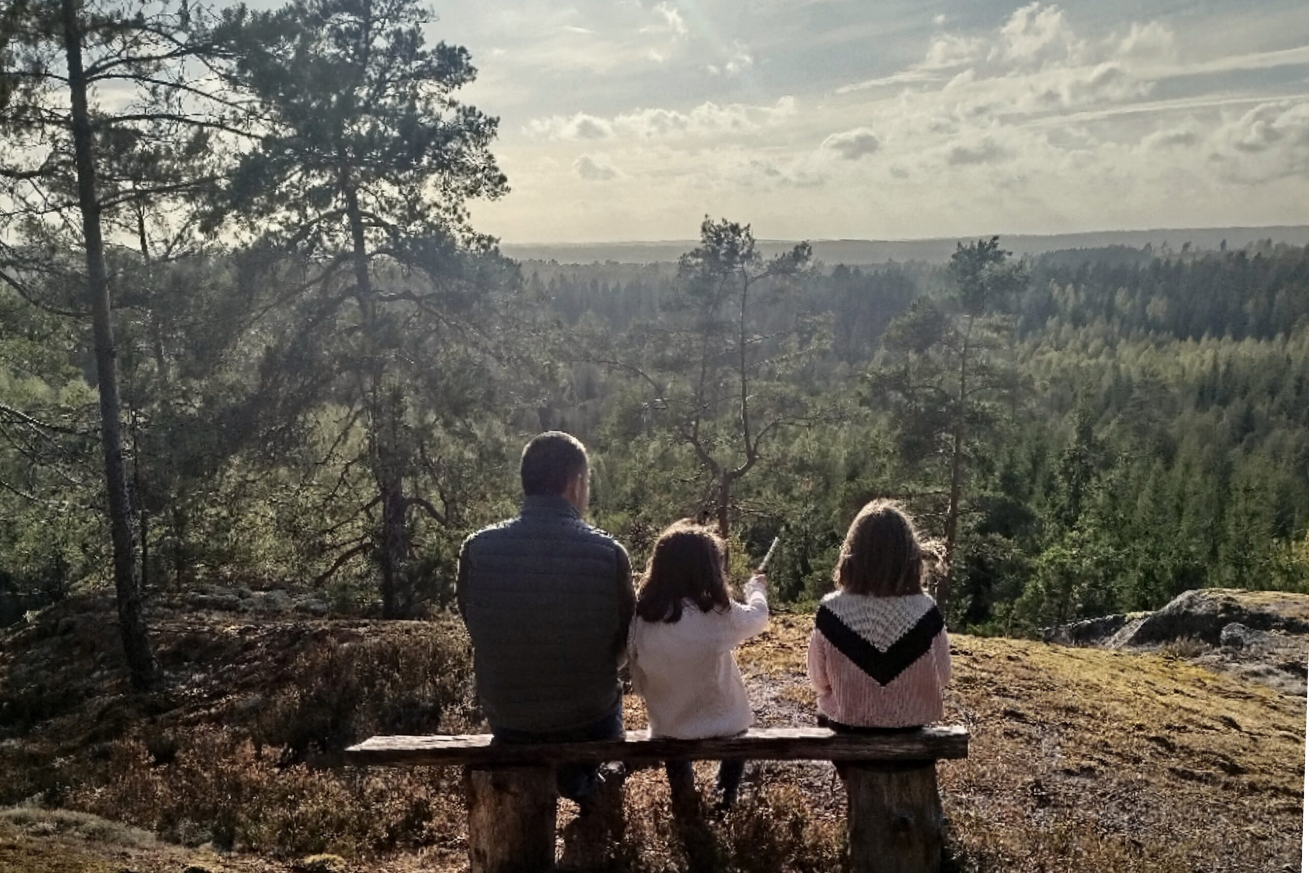 Personer som sitter på en bänk med utsikt över skog och landskap i Småland nära Snokebo Gård