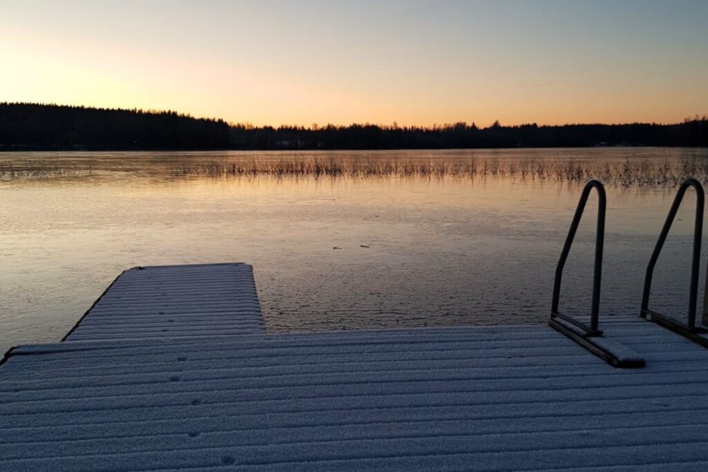 Brygga vid sjön i vinterljus på Snokebo Gård, med is och stilla vatten i kvällsstämning