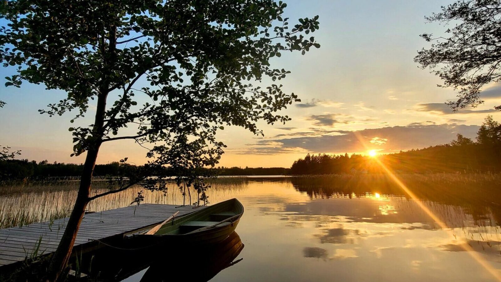 Brygga med roddbåt vid sjön Snesaren i kvällsljus